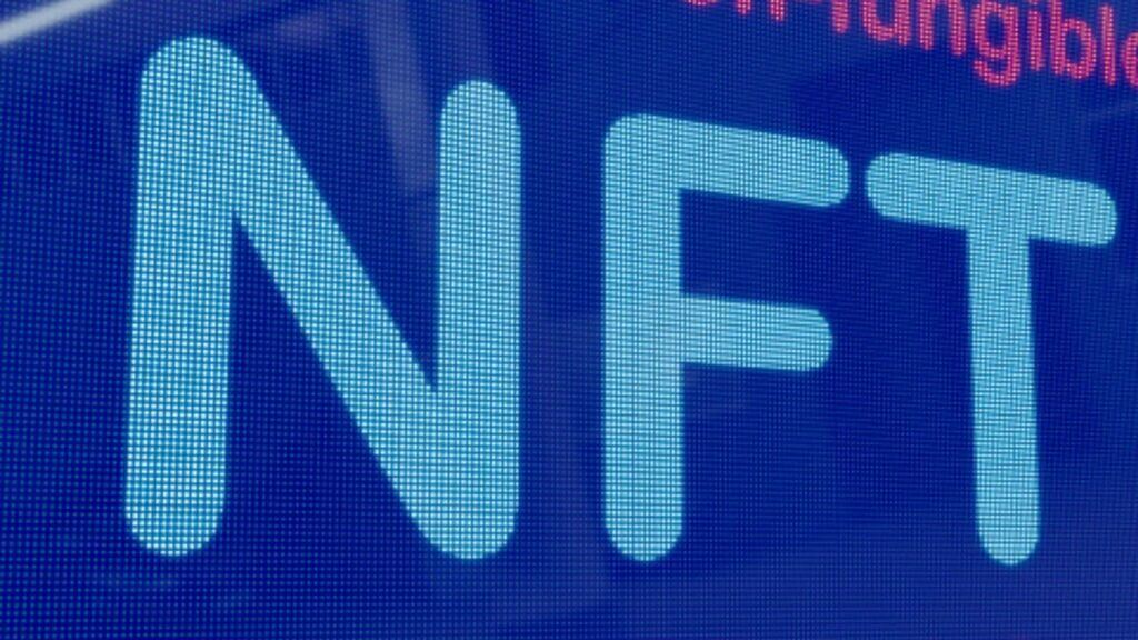 Close-up of the word "NFT" in large blue letters on a digital screen.