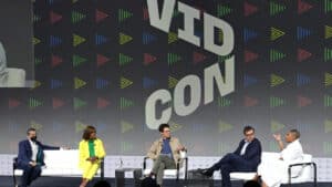 Five panelists seated on stage at VidCon event, engaged in discussion.