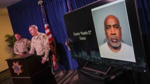 LAS VEGAS, NEVADA - SEPTEMBER 29: A booking photo of Duane "Keefe D" Davis is shown on a television monitor as Clark County Sheriff Kevin McMahill (L) and Las Vegas Metropolitan Police Department Lt. Jason Johansson speak during a news conference at the LVMPD headquarters to brief media members on Davis' arrest and indictment for the 1996 murder of Tupac Shakur on September 29, 2023 in Las Vegas, Nevada. A Nevada grand jury indicted Davis on one count of murder with a deadly weapon in the fatal drive-by shooting of rapper Tupac Shakur.
