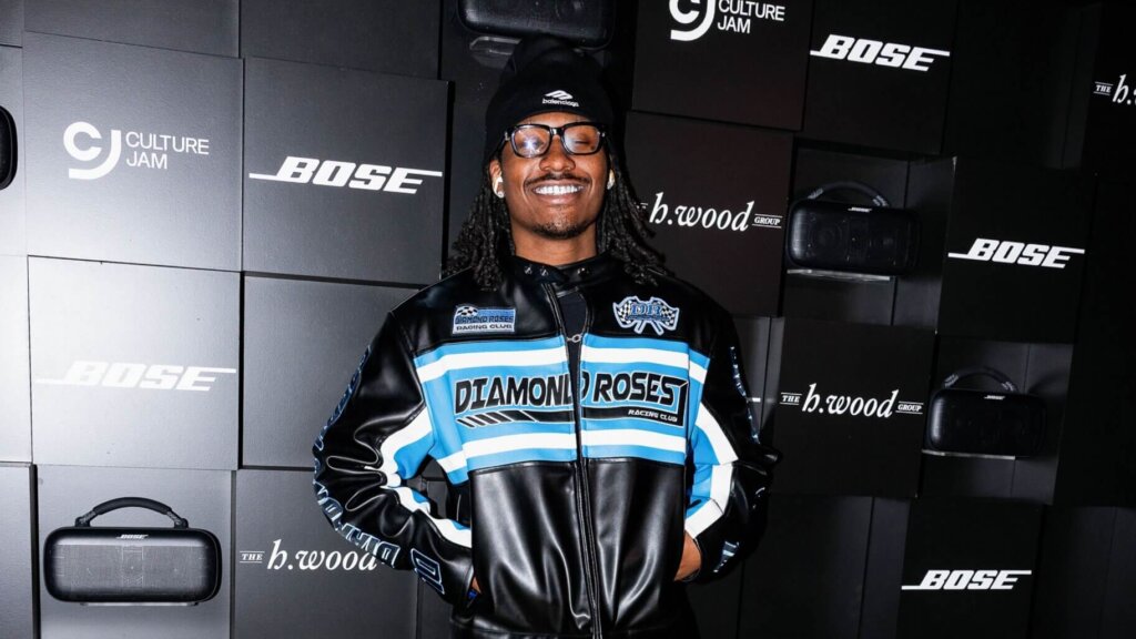 Man in Diamond Roses Racing Club jacket and Balenciaga beanie smiling in front of Bose and Culture Jam backdrop