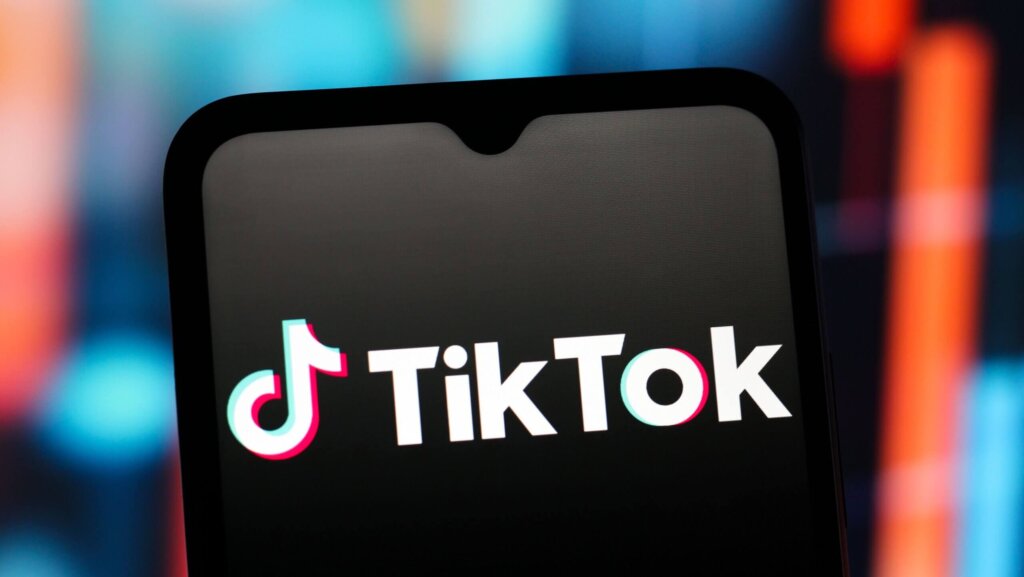 TikTok logo displayed on a smartphone screen with a blurred colorful background