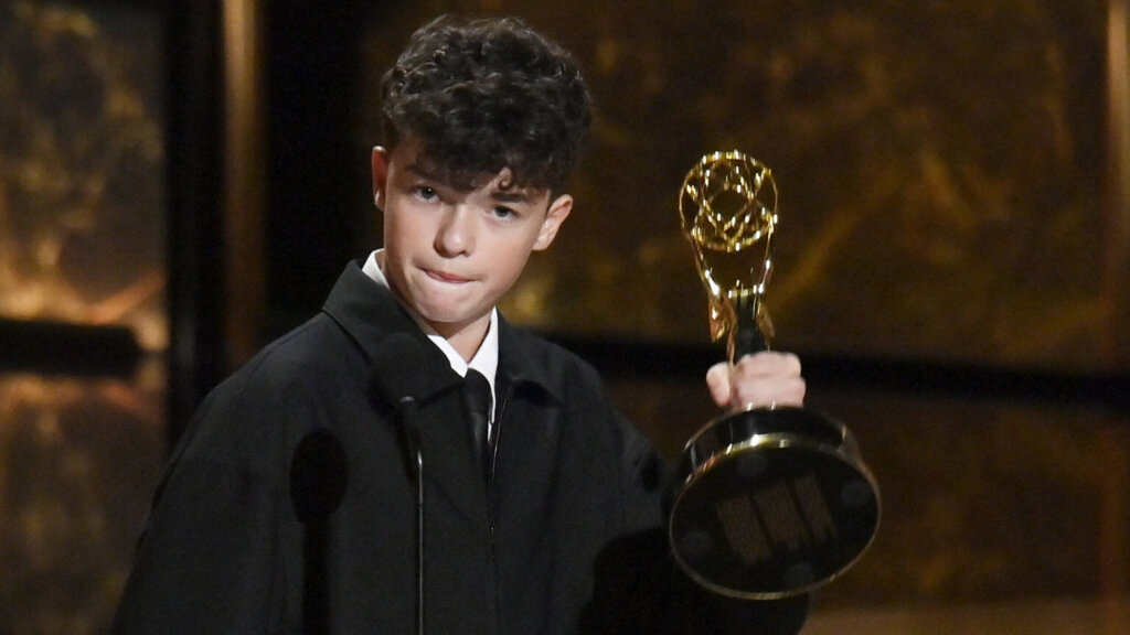 Young man holding an Emmy Award on stage during an awards ceremony