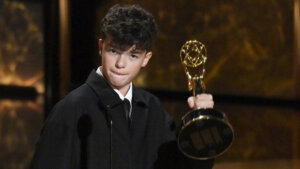 Young man holding an Emmy Award on stage during an awards ceremony