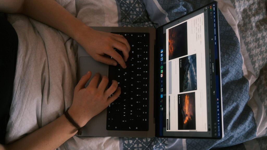 Person typing on a laptop keyboard with a photo editing or browsing webpage open on the screen