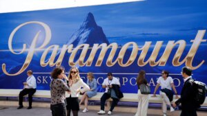 People standing and sitting in front of a large Paramount logo backdrop with a mountain image.
