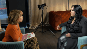 Two women engaged in a seated interview in a studio with professional lighting equipment.
