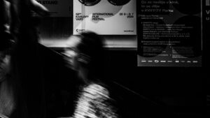 Blurred people on escalator next to posters for the 58th Karlovy Vary International Film Festival 2024